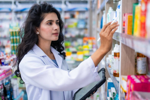 A female pharmacist uses a digital tablet to check the authenticity of medicines while working in a pharmacy.